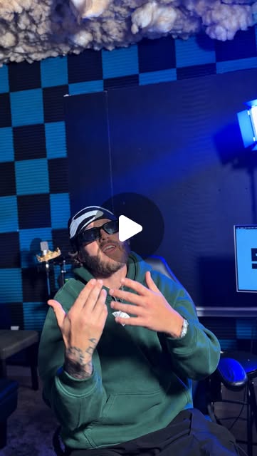 Patrick seated in a blue-lit studio, wearing headphones and a green hoodie.